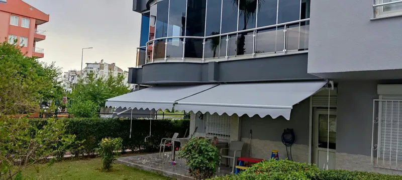 Apartman bahçesinde iki adet gri mafsallı tente – ANT BRANDA