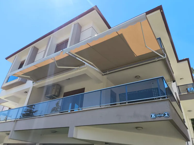 Balkon üzerinde açık bej renkli geniş mafsallı tente sistemi – ANT BRANDA